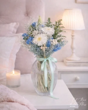 Arreglo floral de estilo romántico con aire limpio y fresco gracias a la combinación de azul y blanco. Materiales utilizados broom, solidalgo, gerbera blanca preservada.
