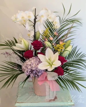 Centro de flores naturales y planta de orquídea. Compuesto por lilium blanco, rosa roja y orquídea en planta blanca. Medidas aprox 80cm altura x 45cm ancho.